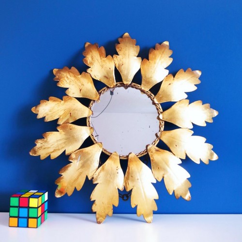 Espejo sol en forja dorada, con diseño de hojas y cadena para colgar. Vintage años 60.